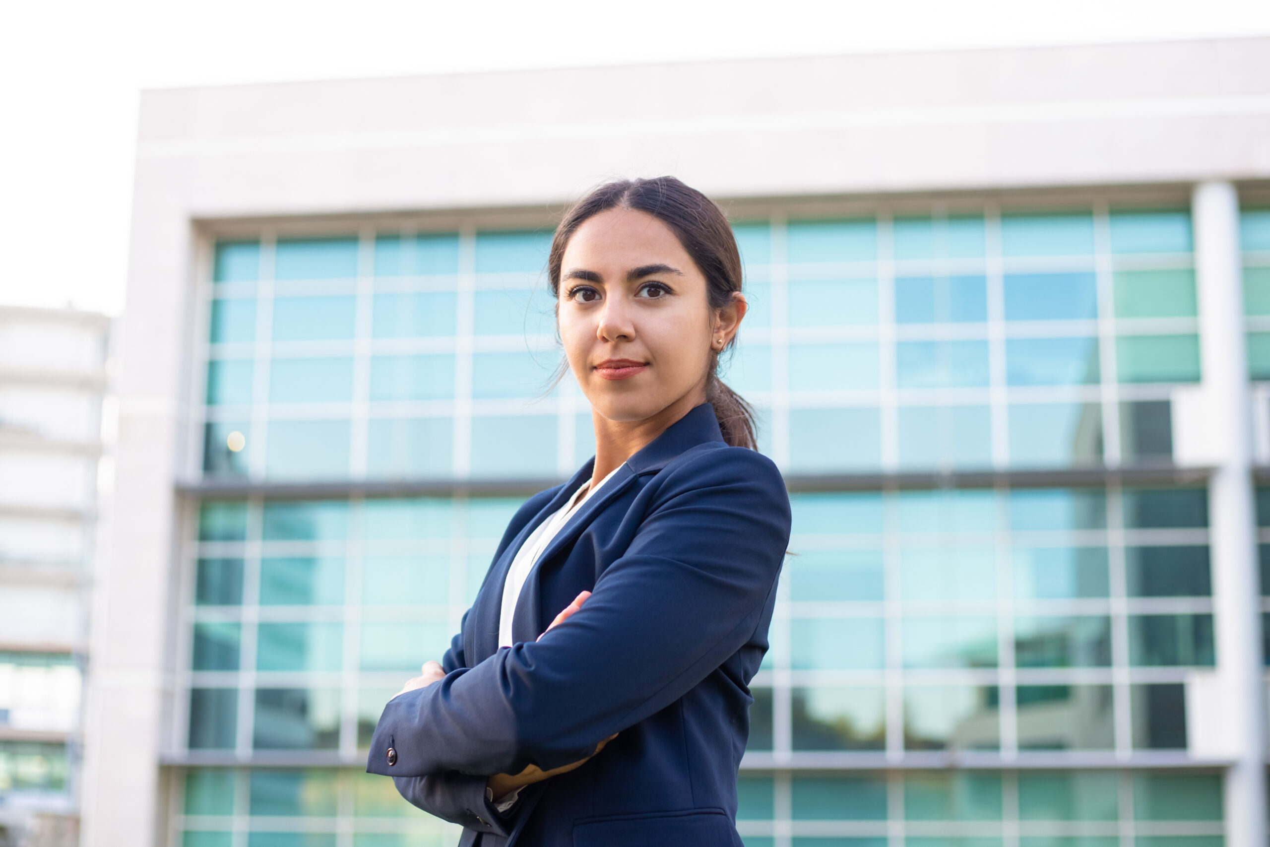 Confident young businesswoman standing with crossed arms