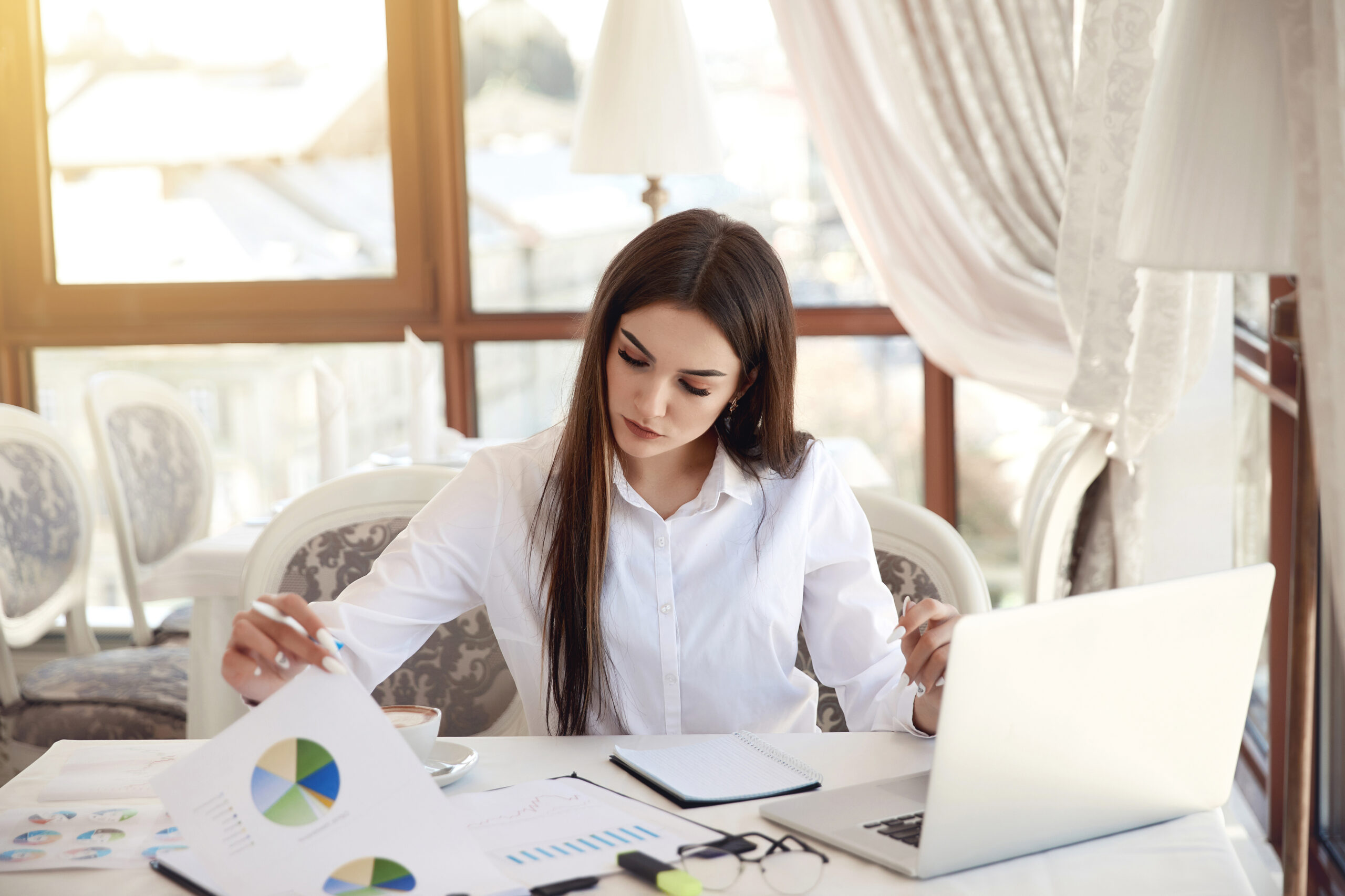 Young brunette business lady is analyzing diagrammes and working